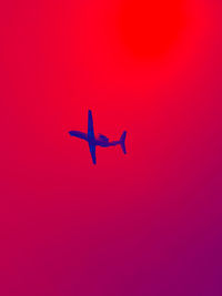 Low angle view of airplane flying against pink sky