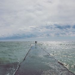 Silhouette person on jetty at calm sea