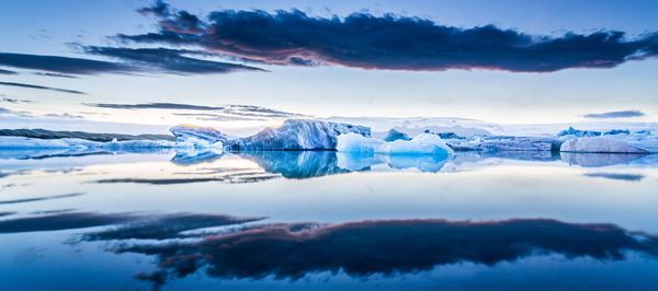 Scenic view of icebergs in lagoon against sky