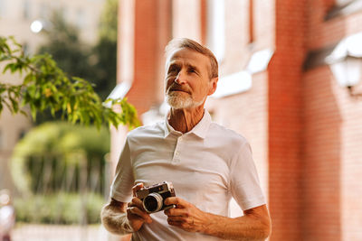 Man photographing with camera against building