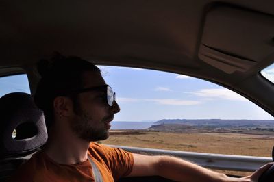 Portrait of a young man looking through car window