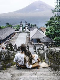 Rear view of couple sitting on staircase at temple