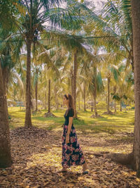 Side view of woman standing by palm trees
