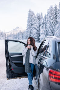 Portrait of young woman sitting on car