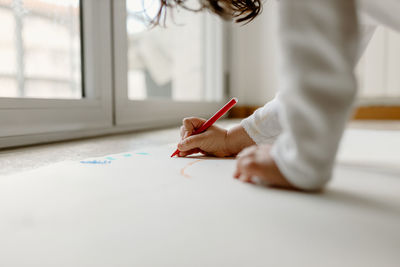 Midsection of woman writing in book at home