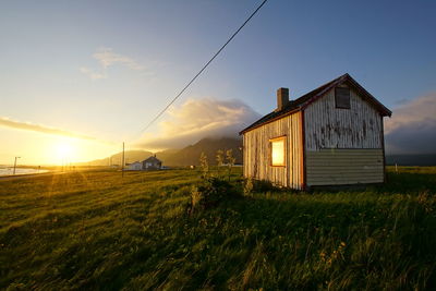 House on field against sky during sunset