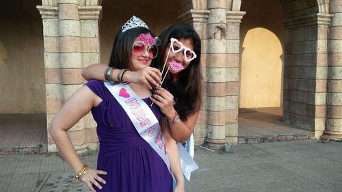 Portrait of smiling young woman with sister wearing bridesmaid sash at vardhman fantasy amusement park