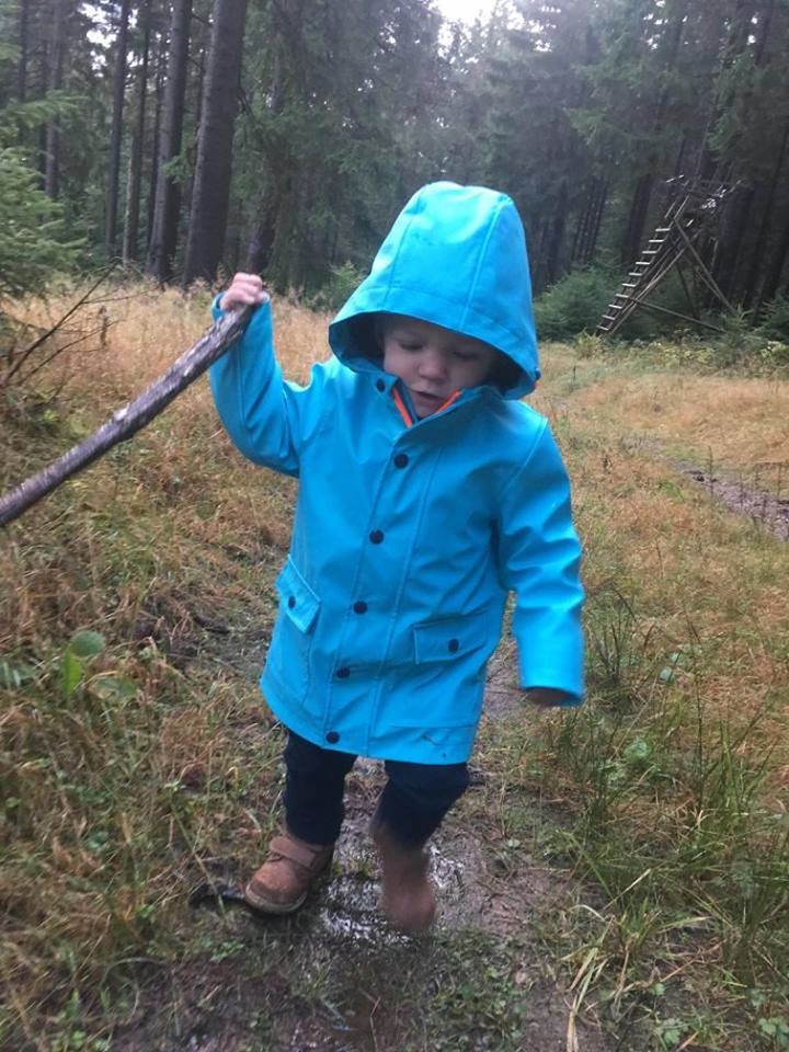 REAR VIEW OF BOY HOLDING UMBRELLA IN FOREST