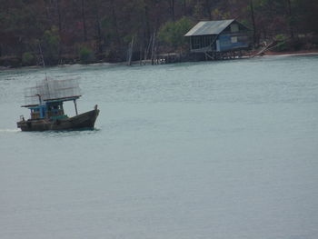 Boat in sea by house against trees