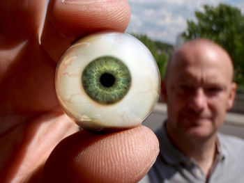 Close-up of man holding artificial eye