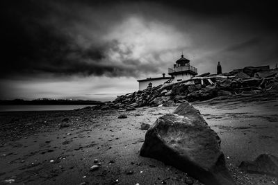 Rocks on beach by sea against sky