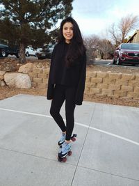 Portrait of smiling young woman standing on footpath