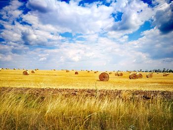 Hay bales on field against sky