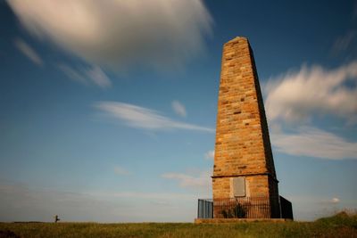 Low angle view of old tower on field against sky