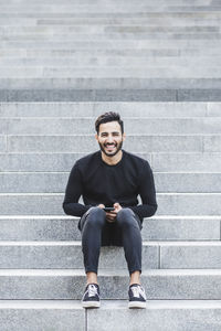 Portrait of smiling young man sitting on staircase