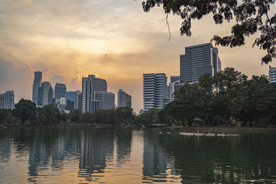 Scenic view of river by buildings against sky during sunset