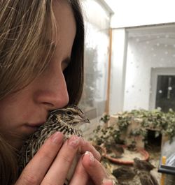 Close-up of woman kissing bird at home