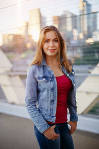 Portrait of smiling young woman standing on bridge