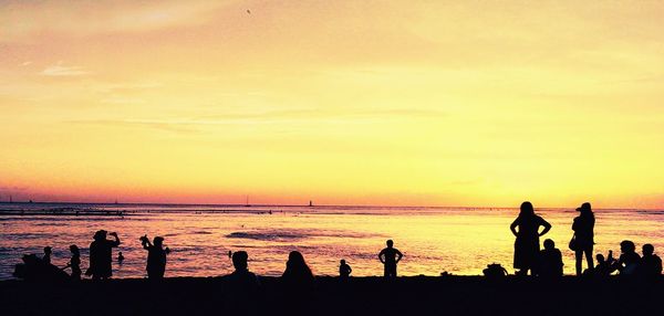 Silhouette people on beach at sunset