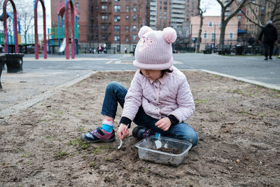 Girl digging in the dirt on the playground on a foggy fall day