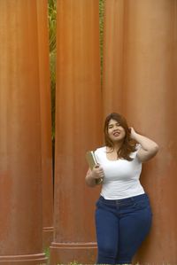 Portrait of young woman with book standing by columns 