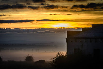 Silhouette buildings against sky during sunset