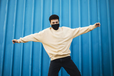 Young man standing against blue wall