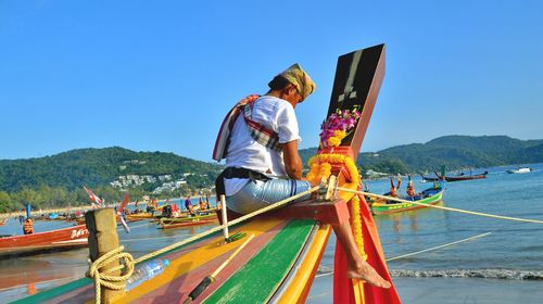 Man on boat in sea against clear sky