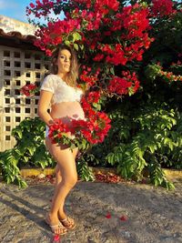 Portrait of beautiful woman standing by flowering plants