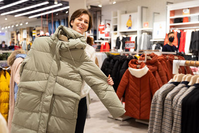 Smiling woman buying jacket in store