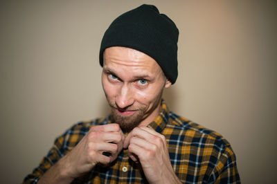 Portrait of young man wearing hat against gray background