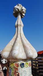 Low angle view of sculpture against building against clear blue sky