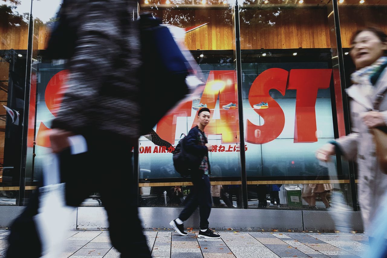 lifestyles, leisure activity, casual clothing, person, standing, communication, front view, text, young adult, three quarter length, street, full length, incidental people, city, sitting, looking at camera, portrait