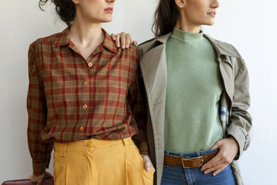 Female friends wearing retro style clothing standing against wall