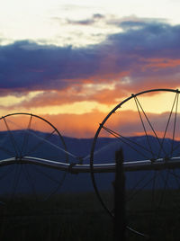 Silhouette fence on field against sky during sunset