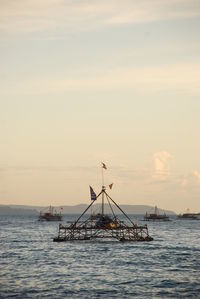 Sailboat in sea against sky during sunset