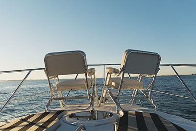 Chairs on shore against clear sky