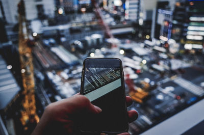 Midsection of person using mobile phone in city