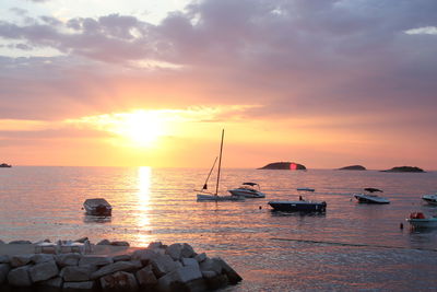 Sailboats on sea against sky during sunset