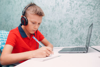 Boy using mobile phone while sitting on table