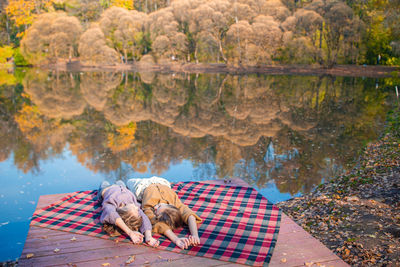 People relaxing on lake by plants