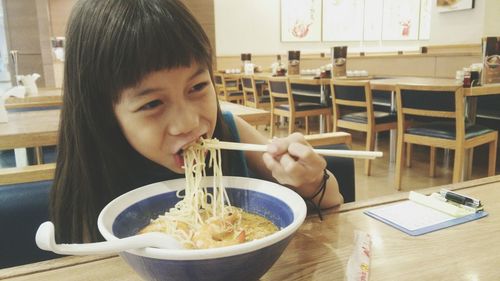 Close-up of girl eating noodles at restaurant