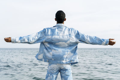 Rear view of man standing by sea against sky