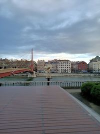 Bridge over river by buildings in city against sky