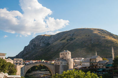 Arch bridge over buildings against sky