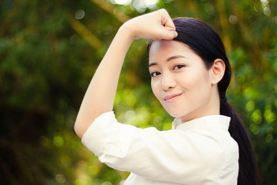 Close-up portrait of young woman showing bicep