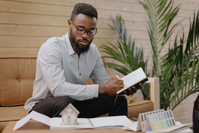 Business professional writing in diary while sitting on sofa