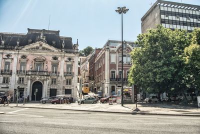 Buildings by street in city against sky