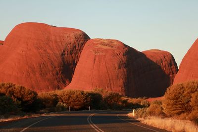 Road leading towards mountains against clear sky