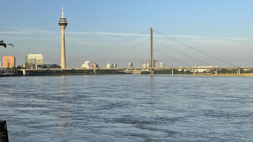 View of bridge over river and buildings against sky